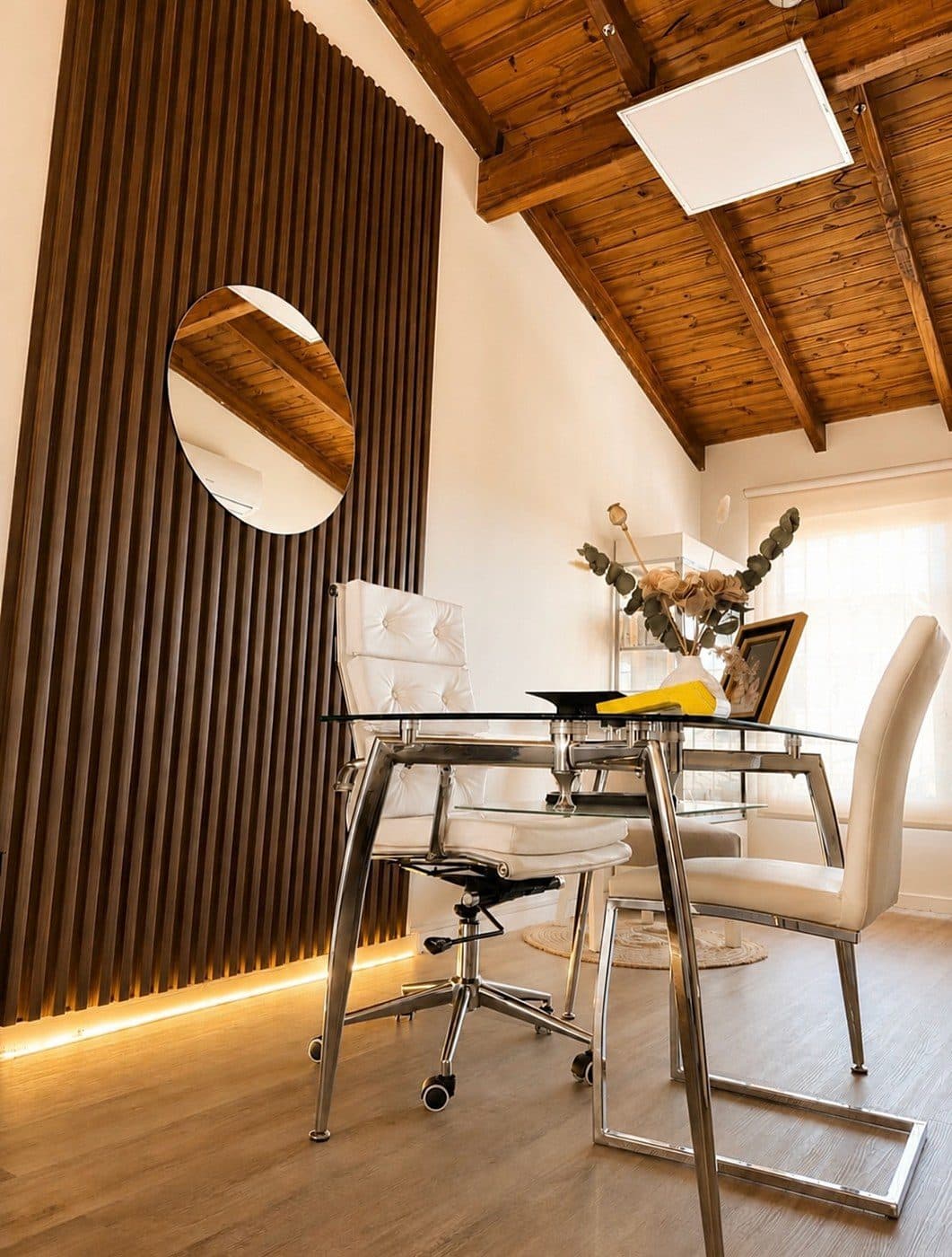 Recepción del estudio de Marianela Maggini en Tupungato: pared de listones de madera, espejo redondo y luz cálida