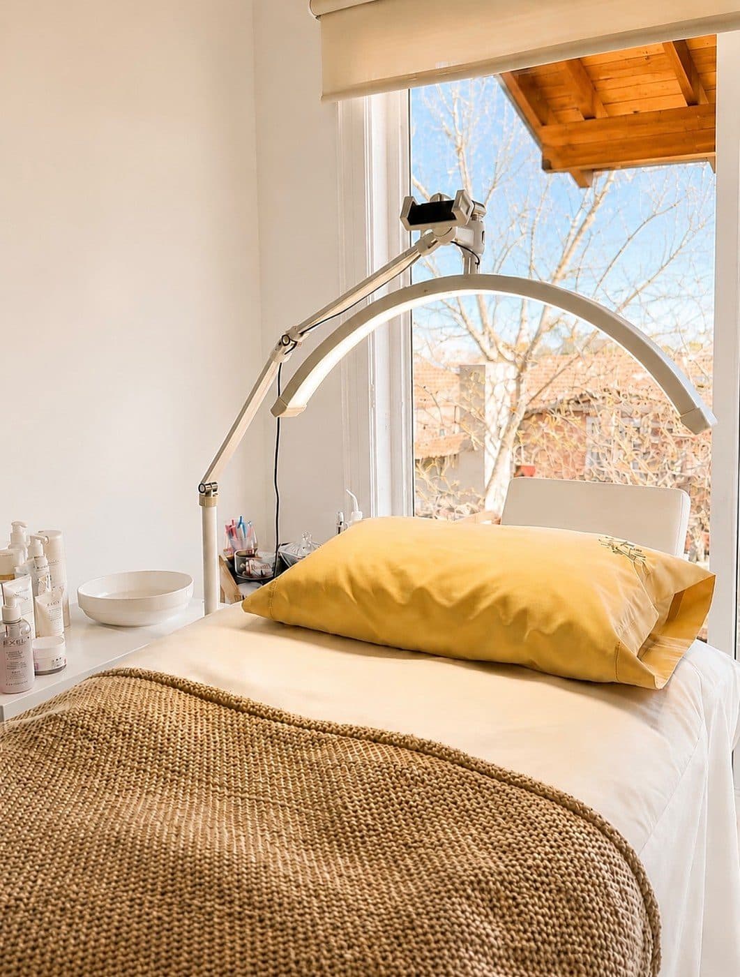 Sala de tratamientos con camilla, lámpara con lupa y luz natural